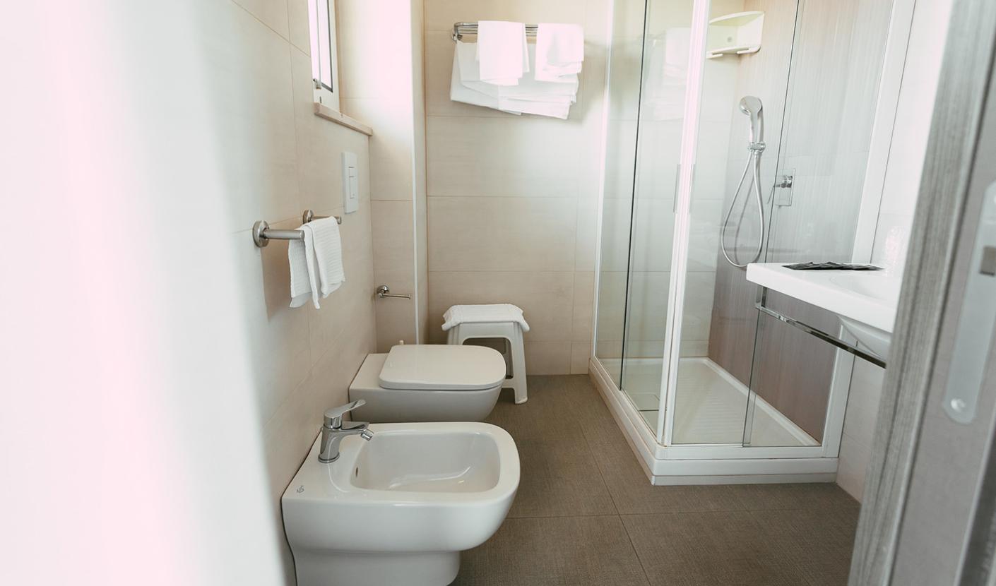 Modern bathroom with shower, bidet, and white towels.