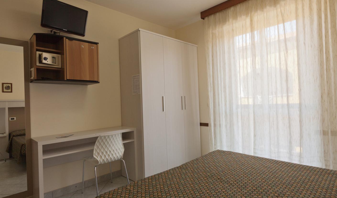Simple room with bed, desk, wardrobe, and wall-mounted TV.