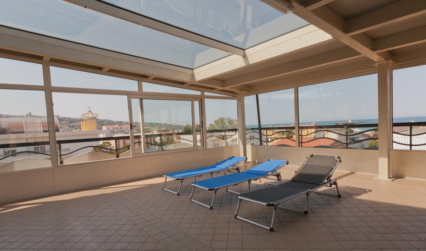Covered terrace with sun loungers and panoramic views of the sea and city.