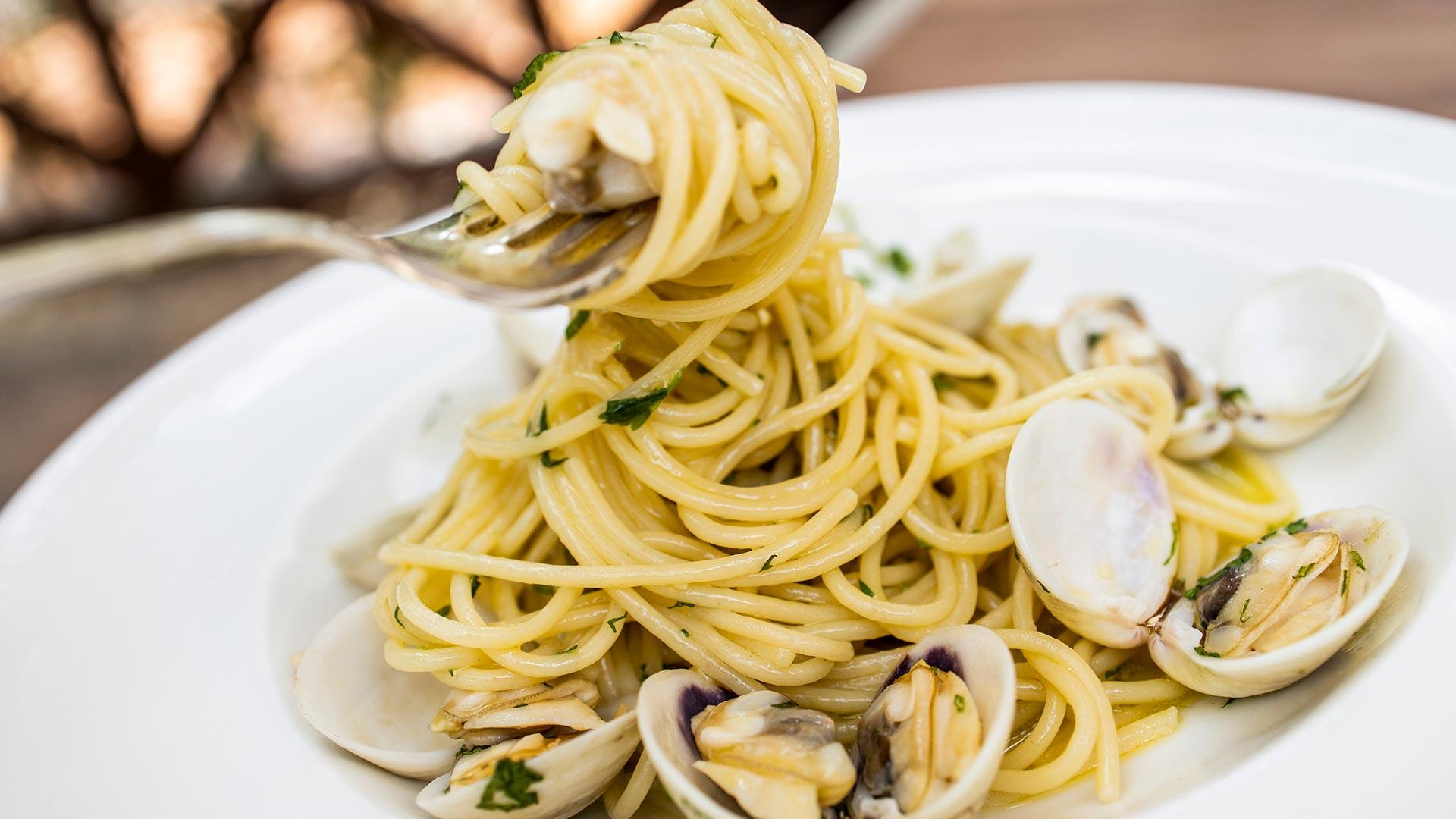 Spaghetti alle vongole con prezzemolo in un piatto bianco.