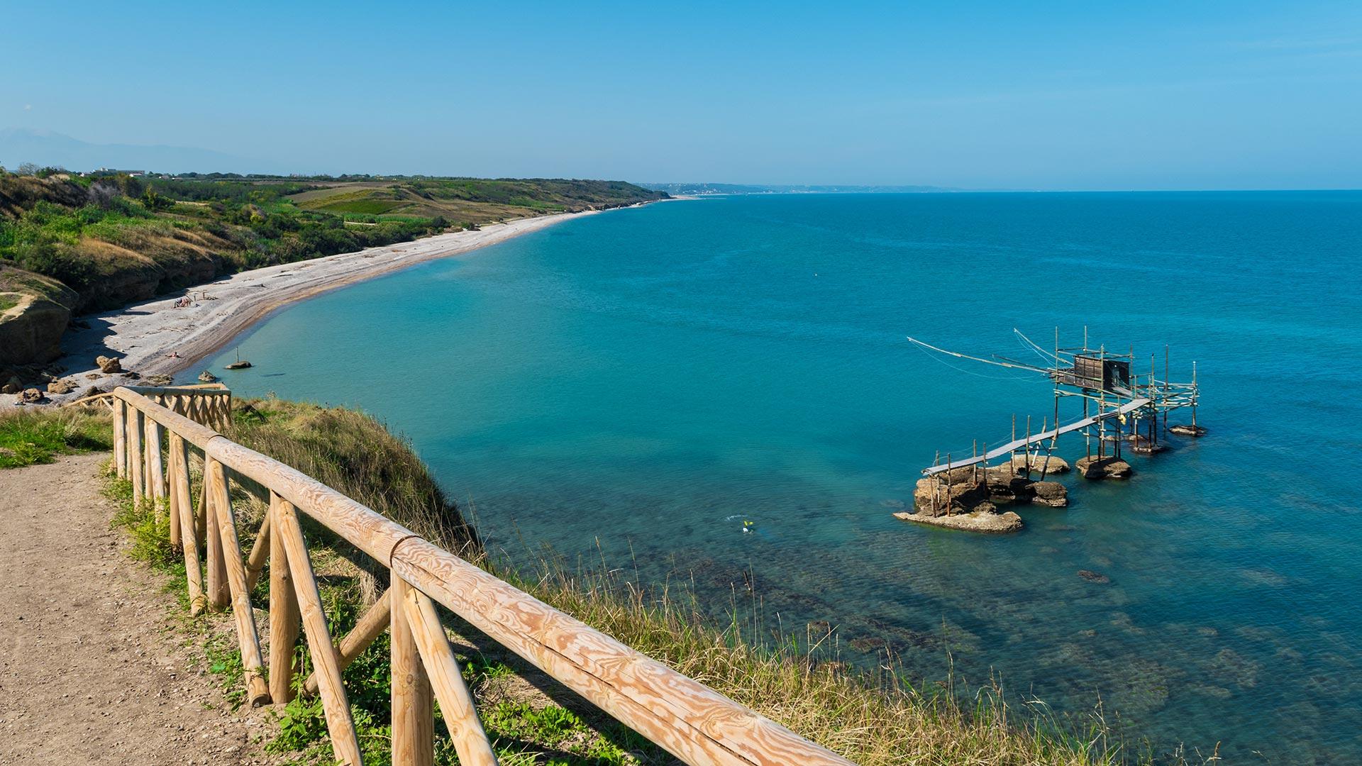 Spiaggia con mare azzurro e trabocco su palafitte in Abruzzo.