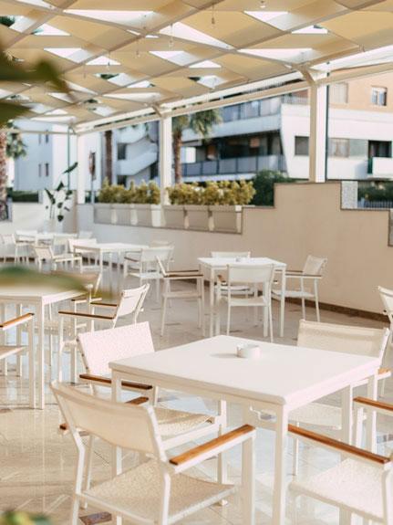 Terrazza con tavoli e sedie bianche in un ambiente moderno e luminoso.
