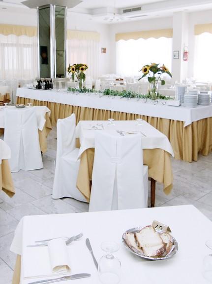 Sala da pranzo elegante con tavoli apparecchiati e decorazioni floreali.