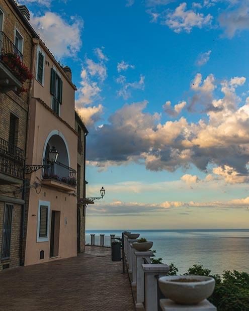 Vista sul mare da una terrazza con edifici storici e cielo nuvoloso.