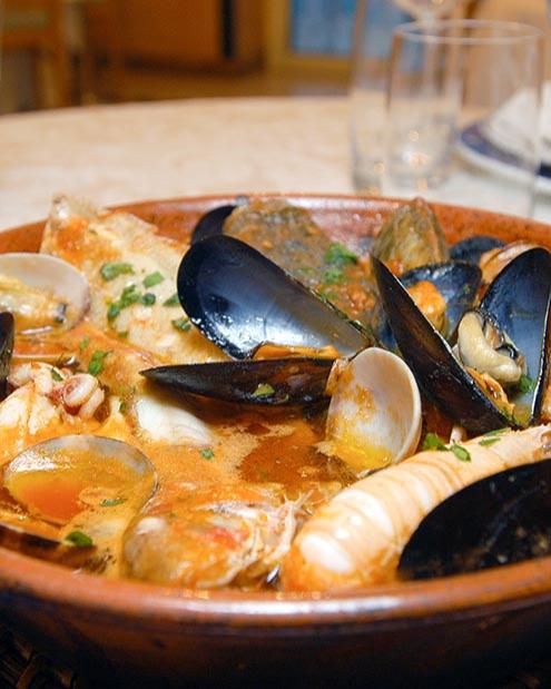 Zuppa di pesce con cozze, vongole e gamberi in una ciotola di terracotta.
