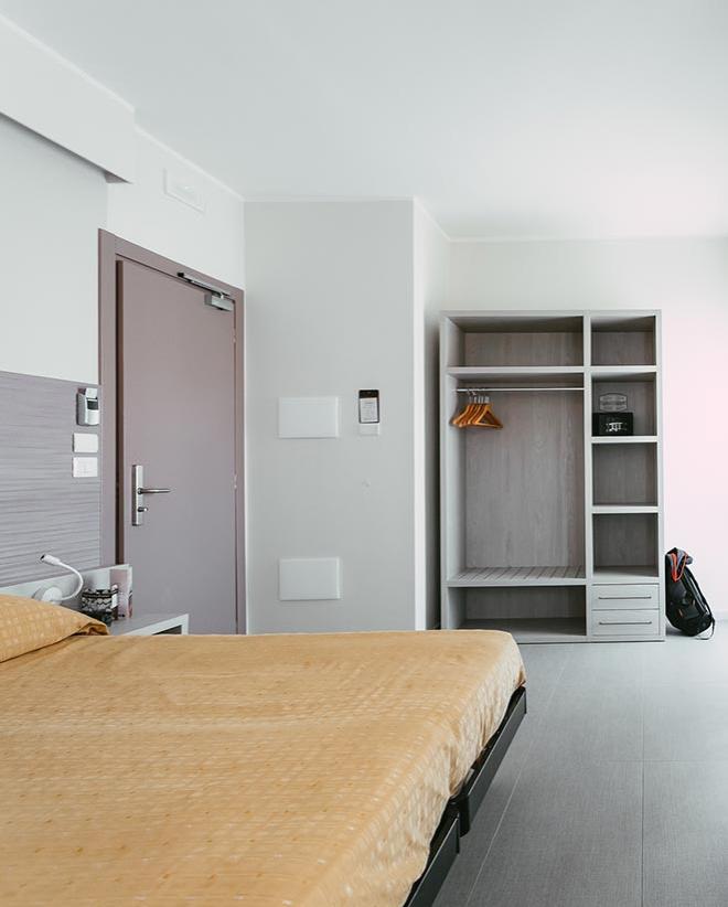 Camera moderna con letto, armadio aperto e porta d'ingresso.