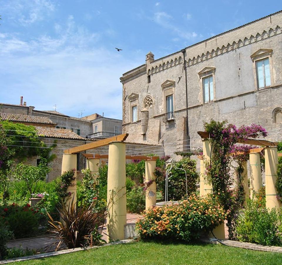 Flower garden with yellow columns in front of an ancient stone building.