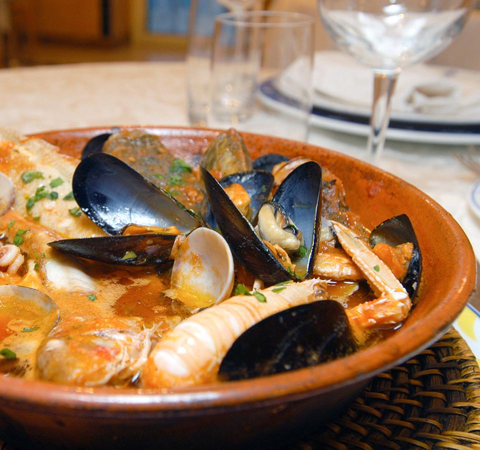 Seafood soup with mussels, clams, and shrimp in a terracotta pot.