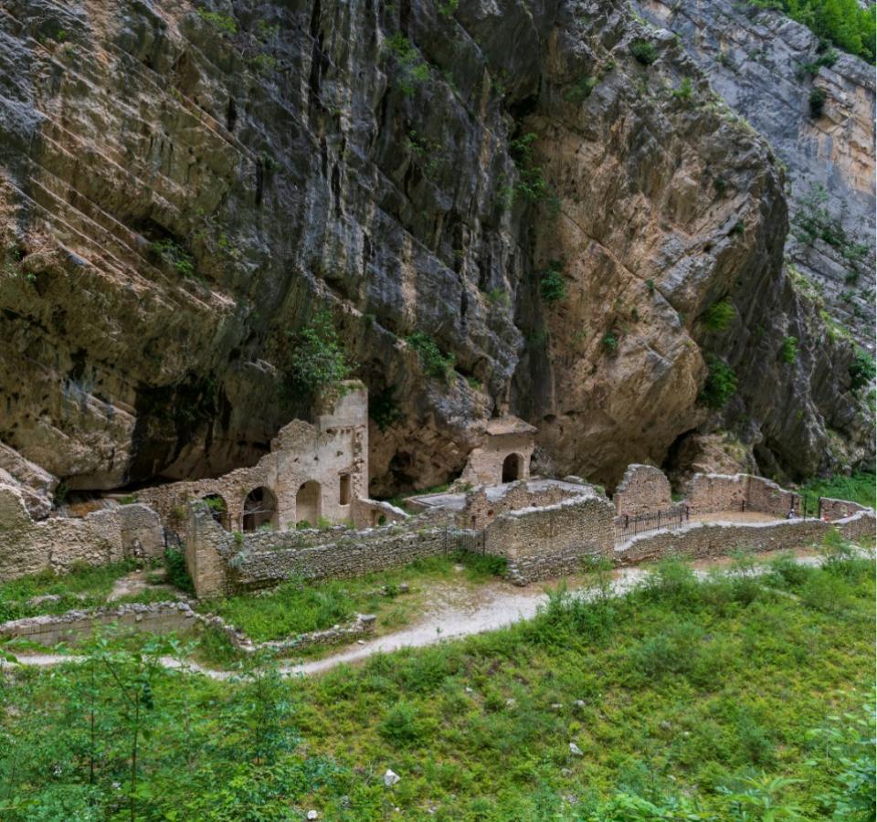 Ancient ruins nestled in a rocky cliff surrounded by nature.