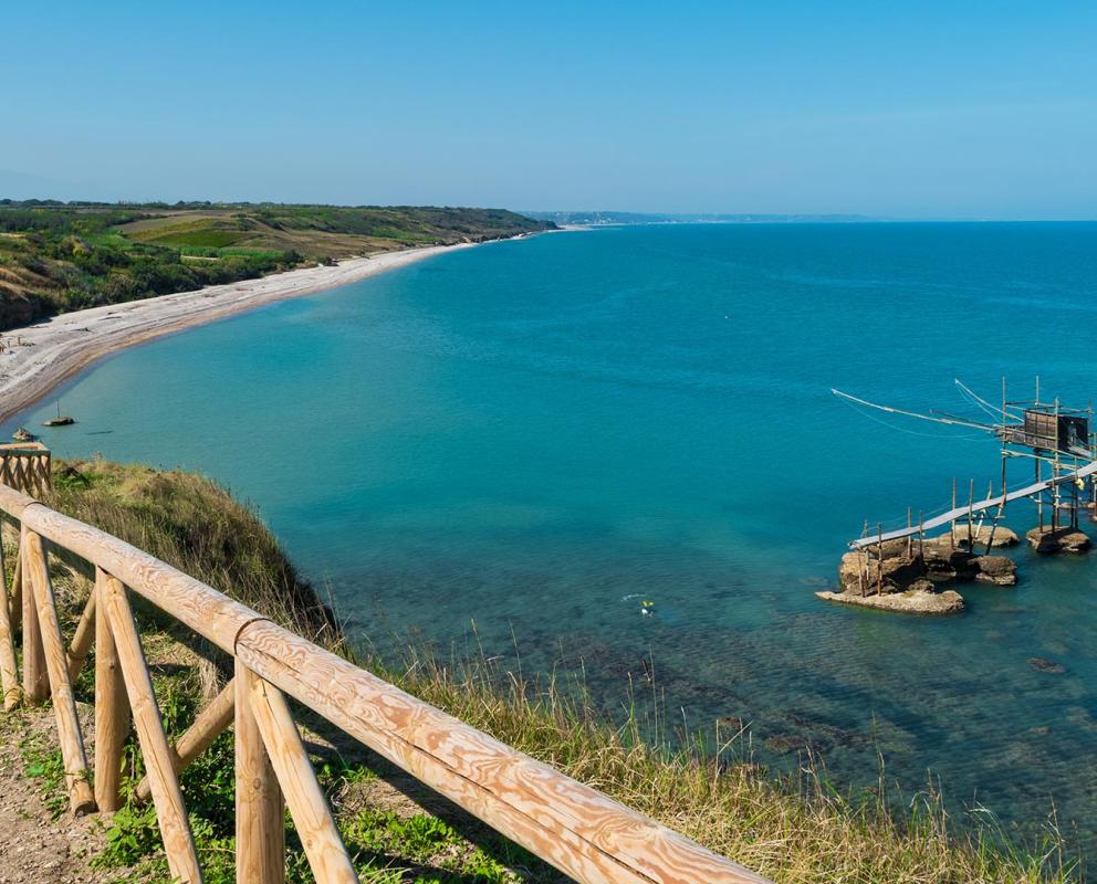 Spiaggia con mare azzurro e trabocco su palafitte in Abruzzo.